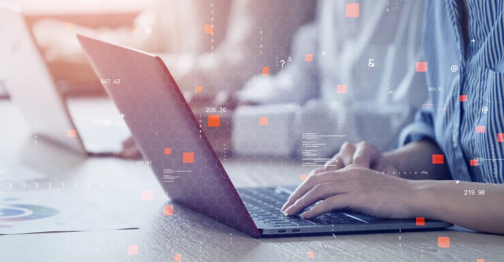 Mains tapant sur un ordinateur portable. Interface holographique avec données, chiffres et symboles. Environnement de travail technologique.